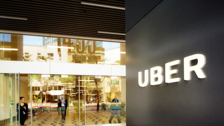 San Francisco, USA - May 12, 2016: Uber headquarters entrance in San Francisco with sign on the right. A woman is leaving the building through the front door. Reflections of Market street in the window.