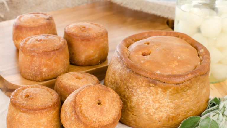 Various pork pies served with pickled silverskin onions garnished with sage leaves.