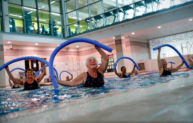 Women exercise using pool noodles during an aqua fit class at a gym in Sunbury-on-Thames after gyms and swimming pools were allowed to reopen