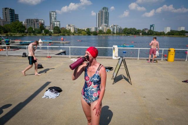 A woman hydrates in the sun after open water swimming at the West Reservoir Centre in north London