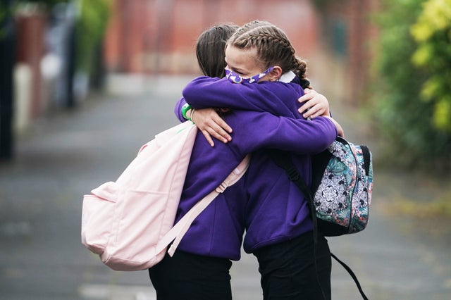 Kadie Lane, right, 11, and Brooke Howourth, 11, hug on their walk to Marden Bridge Middle School in Whitley Bay, Tyne and Wear, for their first day of term, as schools in England reopen to pupils following the coronavirus lockdown