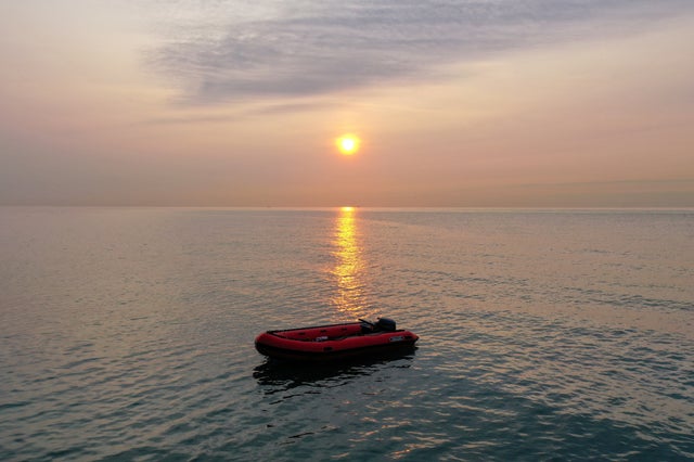 An empty migrant dinghy floats off the beach at St Margaret's Bay after the occupants landed from France in Dover