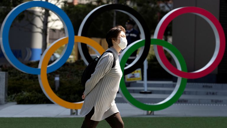  A woman wearing a protective face mask, following an outbreak of the coronavirus disease (COVID-19), walks past the Olympic rings in front of the Japan Olympics Museum in Tokyo