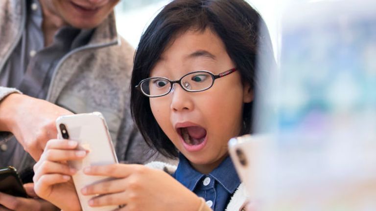 TOKYO, JAPAN - NOVEMBER 03: A girl reacts as she tries an iPhone X at the Apple Omotesando store on November 3, 2017 in Tokyo, Japan. Apple launched the latest iPhone featuring face recognition technology, a large 5.8-inch edge-to-edge high resolution OLED display and better front and back cameras with optical image stabilisation today. (Photo by Tomohiro Ohsumi/Getty Images) 