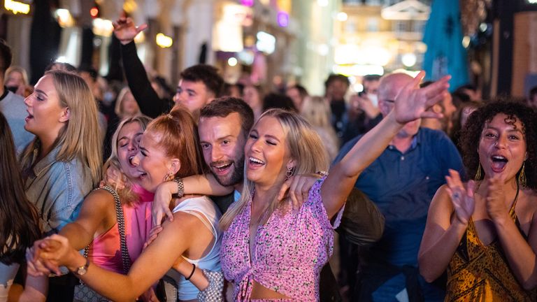 People sing and dance as they watch a street performer in Leicester Square