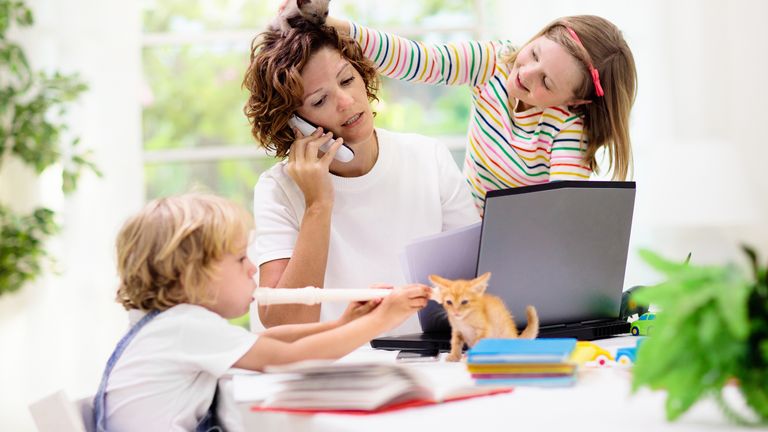 Mother working from home with kids. Quarantine and closed school during coronavirus outbreak. Children make noise and disturb woman at work. Homeschooling and freelance job. Boy and girl playing.