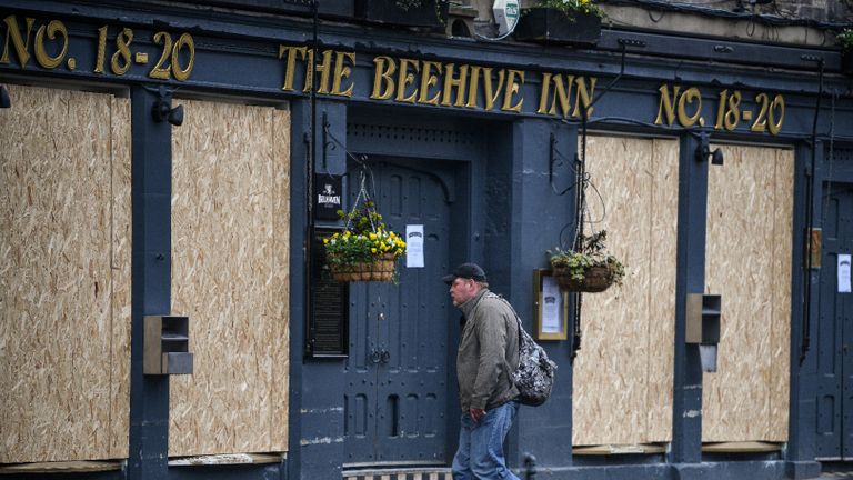 EDINBURGH, SCOTLAND - MARCH 26: A man walks past a boarded up pub in the Grassmarket as people are asked to socially distance themselves amid the coronavirus outbreak on March 26, 2020 in Edinburgh, Scotland. First Minister of Scotland Nicola Sturgeon along with British Prime Minister, Boris Johnson, implemented strict lockdown measures urging people to stay at home and only leave the house for basic food shopping, exercise once a day and essential travel to and from work.The Coronavirus (COVID-19) pandemic has spread to at least 194 countries, claiming over 21,000 lives and infecting over 470,000 people. There have now been over 9,500 diagnosed cases in the UK and 463 deaths. (Photo by Jeff J Mitchell/Getty Images)